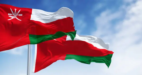 stock image National flags of Oman waving in the wind on a clear day. Vertical red stripe with Oman emblem and three horizontal stripes: white, red, and green. 3d illustration render. Rippling fabric