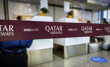 Doha, QA, 22 Mayıs 2022; Katar Havayolları 'nın yakın çekimi havaalanı kayıt gişesinde kurdele damgalı. Görünür logolar arasında Katar Havayolları ve Oneworld ittifakı yer alıyor.