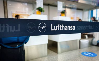 Lufthansa havaalanı giriş alanında bariyer olarak damgalanmış. Sayaç ve yolcuların bulanık arkaplanlı bantlarına odaklan. Seyahat ve havayolu endüstrisi konsepti