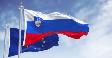 Slovenya ve Avrupa Birliği bayrakları açık bir günde birlikte dalgalanıyor. 1 Ocak 2007 'den beri Avro Bölgesi Üyesi. Kusursuz 3 boyutlu animasyon. Yavaş çekim döngüsü. Seçici odak