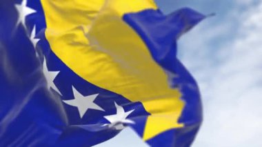 Bosna-Hersek ulusal bayrağının rüzgarda dalgalandığı yakın plan çekimleri. Sarı üçgen ve beyaz yıldızlı mavi alan. Kusursuz 3 boyutlu animasyon. Yavaş çekim döngüsü. Seçici odaklanma. 4k