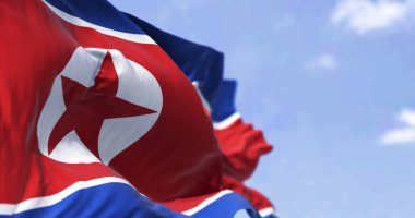 Açık bir günde Kuzey Kore bayrağının rüzgarda dalgalandığı yakın çekim. Yıldız ve mavi beyaz çizgili kırmızı bayrak. 3 boyutlu çizim, dalgalı kumaş. Seçici odak