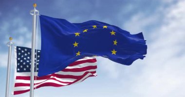 Avrupa Birliği ve ABD bayrakları açık gökyüzü altında resmi bayrak direkleri üzerinde birlikte dalgalanıyor. Uluslararası ilişkiler, diplomasi, ortaklık ve işbirliği kavramı. Yavaş çekim döngüsü