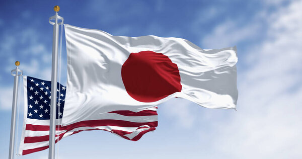 Японские и американские национальные флаги размахивают ветром в ясный день. 3D иллюстрация рендеринга. Сохнущий текстиль. Выборочный фокус. Флаг размахивания