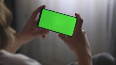 Elinde yeşil ekranlı bir telefon var.