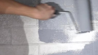 Bir silindirli el duvarı boyar.