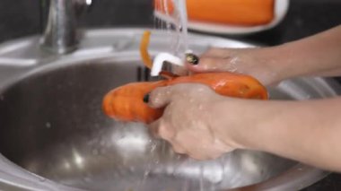 Bir havucun kabuğunu soyan dişi eller.