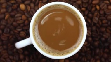 coffee in a white mug and coffee beans spin in a circle top view