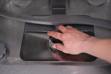 Kadının eli bulaşık makinesindeki filtreyi kontrol ediyor..