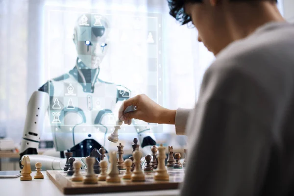 男の子の決意は デジタルで未来的なインターフェースを使用してロボットとチェスを演じるように示しています — ストック写真