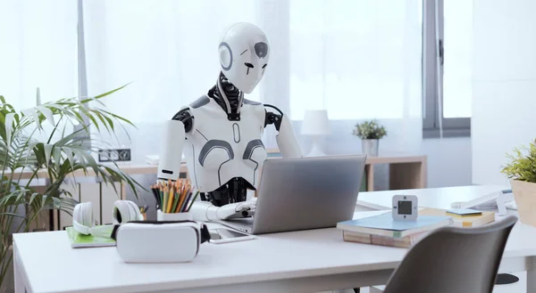 Robot Przypominający Człowieka Siedzi Przy Biurku Biurze Używając Laptopa Pokazania — Zdjęcie stockowe