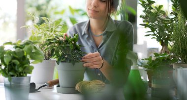 Evde poz veren genç bahçıvan ve bir sürü yemyeşil bitki.