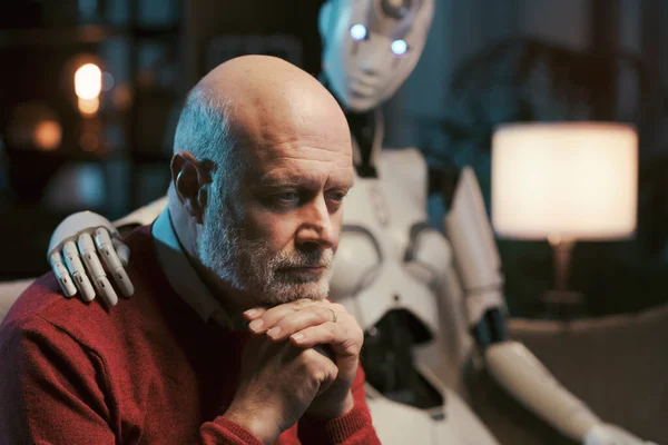 Sad lonely man at home alone sitting on the couch with his caring AI robot