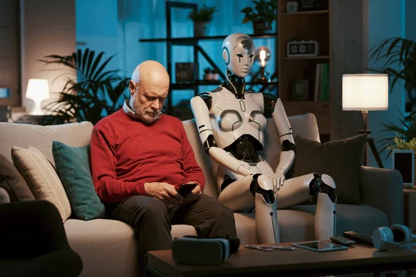 Mężczyzna Siedzi Kanapie Domu Swoim Humanoidalnym Robotem Łączy Się Smartfonem — Zdjęcie stockowe