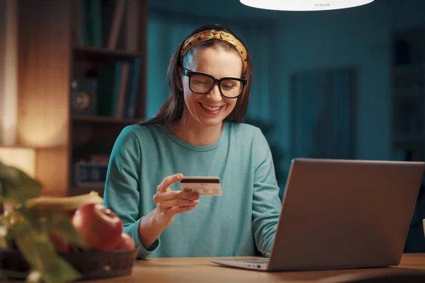 Happy excited woman connecting with her laptop at home and doing online shopping using a credit card