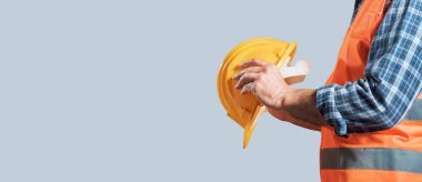 Kişisel koruyucu ekipman giyen ve elinde sıkı bir şapka tutan profesyonel bir işçi: iş konseptinde güvenlik