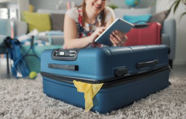 Mutlu kadın seyahat için hazırlanıyor ve internete bağlanıyor