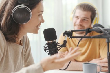 Young man and woman wearing headphones and doing a live podcast for their channel, communication and technology concept