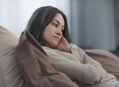 Sad young woman sitting on the bed at home, she is lonely and depressed