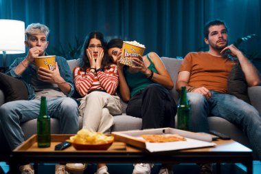 Bir grup arkadaş evdeki kanepede oturuyor ve birlikte TV 'de korku filmleri izliyorlar.