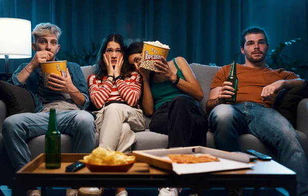 自宅でソファーに座り テレビでホラー映画を見ている友人のグループ — ストック写真