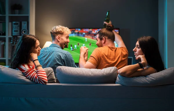 ボーイフレンドがテレビでサッカーを見ている間 ボーイフレンドが一緒に話したりゴシップしたりする退屈な女の子たち — ストック写真