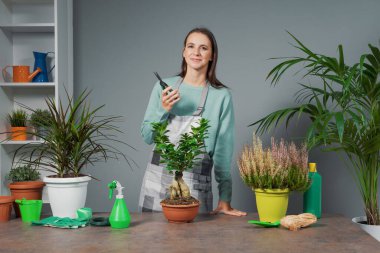 Çevrimiçi bahçıvanlık dersleri veren kadın, bitki ve bahçe malzemeleri gösteriyor.