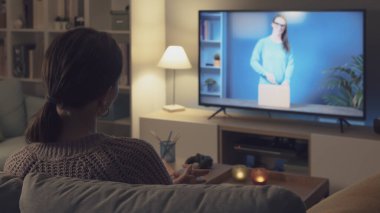 Kanepede dinlenen ve akıllı televizyonunda boks videosu izleyen bir kadın.
