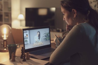 Çevrimiçi olup satranç öğrenen bir kadın çevrimiçi kurslar izliyor.