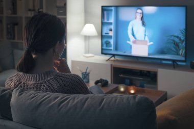 Kanepede dinlenen ve akıllı televizyonunda boks videosu izleyen bir kadın.