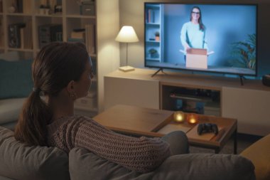 Kanepede dinlenen ve akıllı televizyonunda boks videosu izleyen bir kadın.
