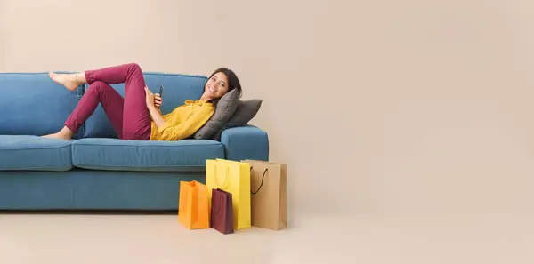 Glückliche Junge Frau Die Mit Einkaufstüten Auf Der Couch Liegt Stockbild