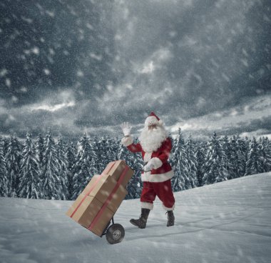 Cesur Noel Baba, karın altında Noel hediyeleri dağıtıyor. Bir el arabası sürüyor.