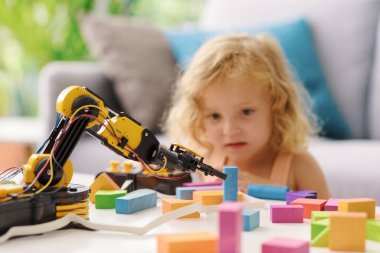 Evde robotik kol oyuncağıyla oynayan tatlı kız: dijital yerliler ve öğrenme teknolojisi konsepti