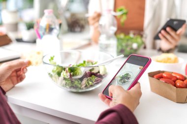 İnsanlar öğle yemeği arası veriyor, salata yiyor ve akıllı telefonlarını, telefon bağımlılığı konseptini kullanıyorlar.