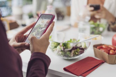 İnsanlar öğle yemeği arası veriyor, salata yiyor ve akıllı telefonlarını, telefon bağımlılığı konseptini kullanıyorlar.