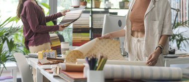 Ofislerinde çalışan genç yaratıcı iç mimarlar ve dekoratörler, kumaş örneklerini ve farklı türde duvar kağıtlarını, yaratıcılığı ve ev yenileme konseptini kontrol ediyorlar.