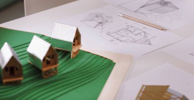 Bir mimarın masasında, projesinin ve tasarım çizimlerinin bir modeli görülebilir. 
