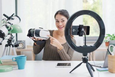 İçerik yaratıcısı akıllı telefon kullanarak sosyal medya için video çekiyor. Elinde bir VR kulaklığı var.