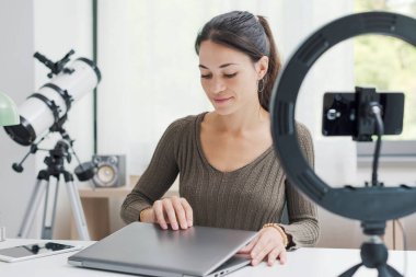 Sosyal medya için videolar oluşturan nüfuzlu kişi, bir dizüstü bilgisayar, akıllı telefon ve halka ışığı kullanıyor