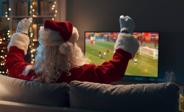 Mutlu Noel Baba kanepede dinleniyor ve TV 'de futbol maçı izliyor.