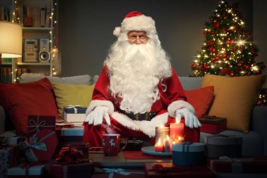 Evdeki koltukta mutlu noel baba, kameraya gülümsüyor, Noel kutlaması konsepti.