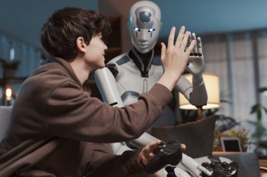 Mutlu çocuk ve yapay zeka beşlik çakıyor, evde video oyunları oynuyorlar, insan-robot etkileşimi konsepti.
