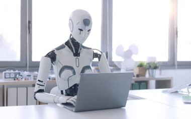İnsanımsı bir robot, bir ofiste dizüstü bilgisayarda çalışır ve tekrarlanan ve can sıkıcı görevlerde otomasyonun faydasını gösterir..