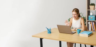 Genç bir kadın masasında oturuyor ve bir arkadaşını internetten bilgisayar, teknoloji ve iletişim konseptiyle arıyor.