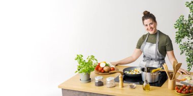 Kadın taze sebzelerle sağlıklı bir makarna hazırlıyor, kameraya gülümsüyor, boşluğu kopyalıyor.