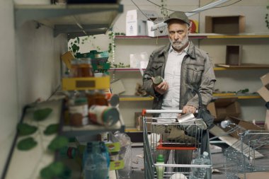 Mahvolmuş bir süpermarkette, yiyecek kıtlığı, savaş ve açlık konsepti olan bir arabayı iten umutsuz son sınıf öğrencisi.