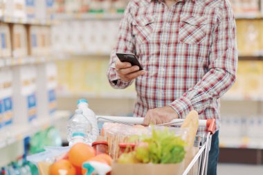 Markette akıllı telefon kullanan müşteri ellerini kapatır.