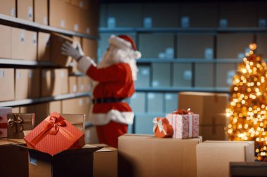 Depoda çalışan Noel Baba, Noel hediyeleriyle dolu posta kutuları hazırlıyor.
