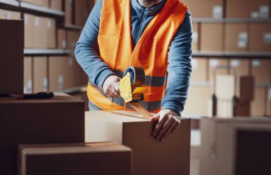 Depo çalışanı bir teslimat kutusunu bantlıyor ve bir sevkiyat, lojistik ve teslimat hizmeti konsepti hazırlıyor.